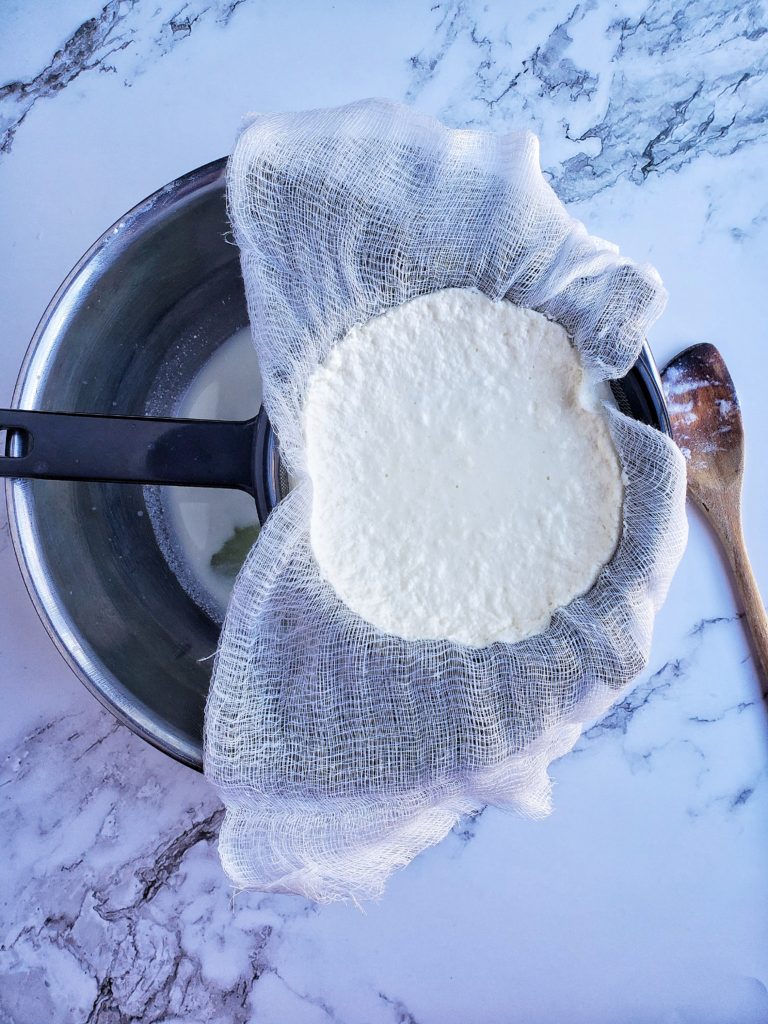 Ricotta cheese straining in a bowl