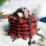 Stack of red velvet pancakes with cream cheese topping