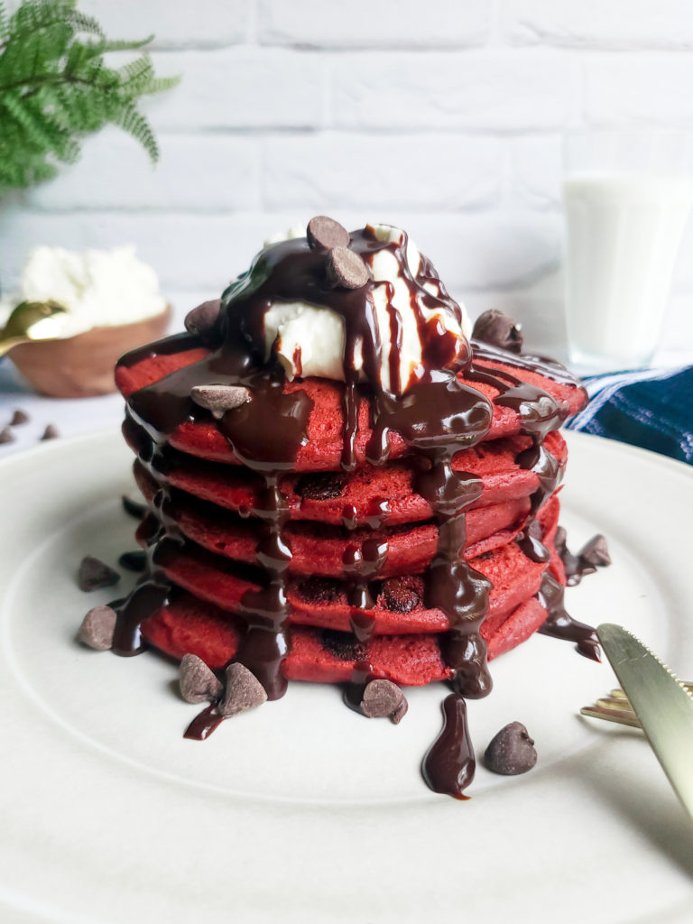 Stack of red velvet pancakes with cream cheese topping