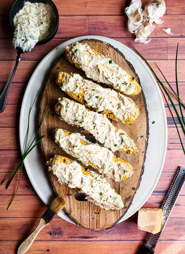 Platter of grilled corn slathered with garlic parmesan sauce