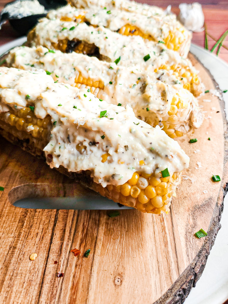 Grilled corn on a platter with garlic parmesan sauce