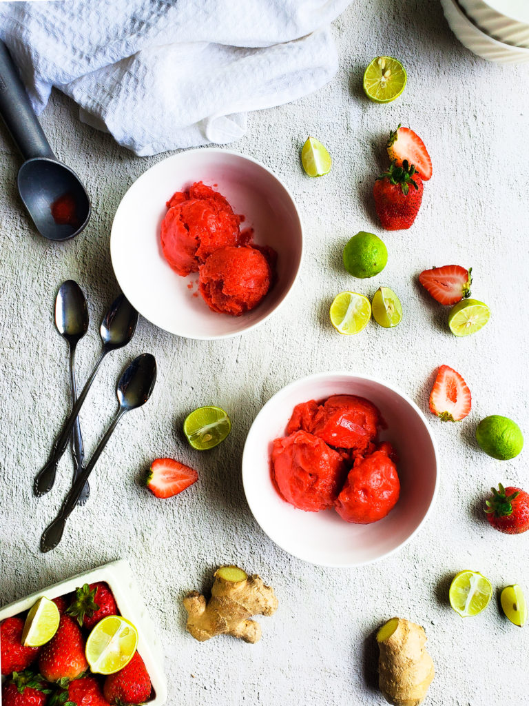 Overhead shot of two bowls of strawberry key lime sorbet in bowls with sliced strawberries and key limes