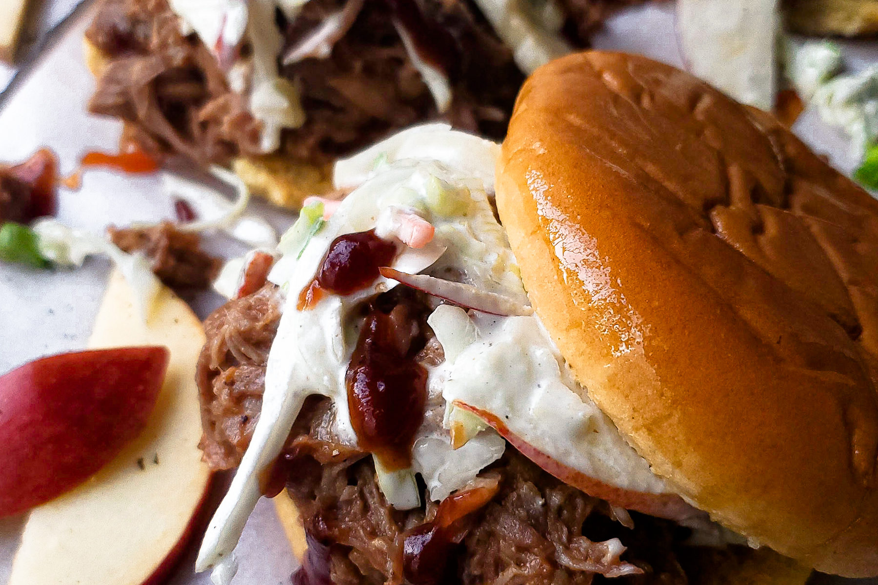 Close up of pulled pork sandwich topped with an apple slaw