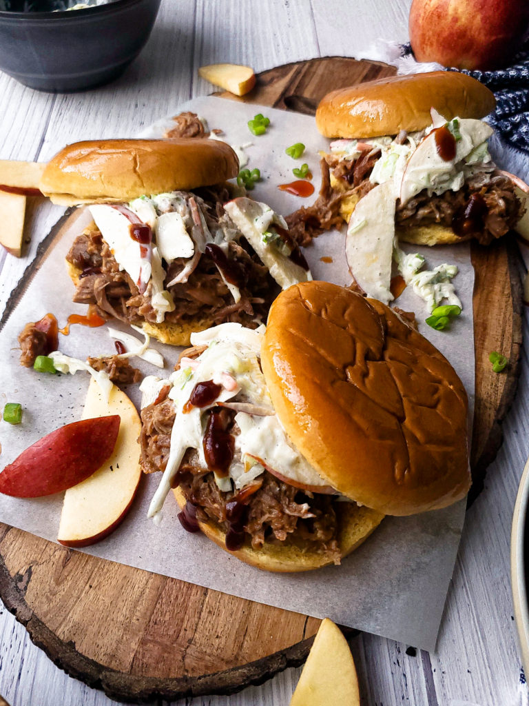 Three pulled pork sandwiches topped with slaw on a platter