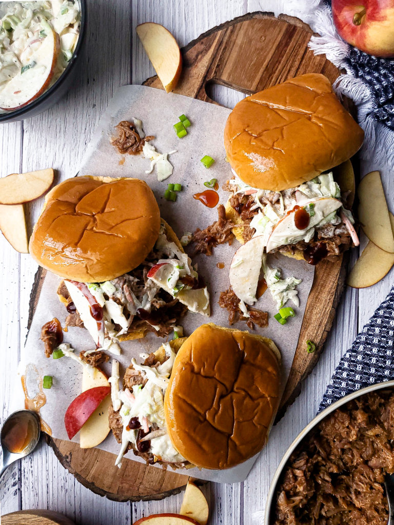Overhead shot of Three pulled pork sandwiches topped with slaw on a platter