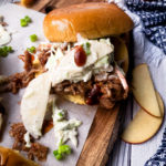 Close up of an assemble pulled pork sandwich with apple slaw
