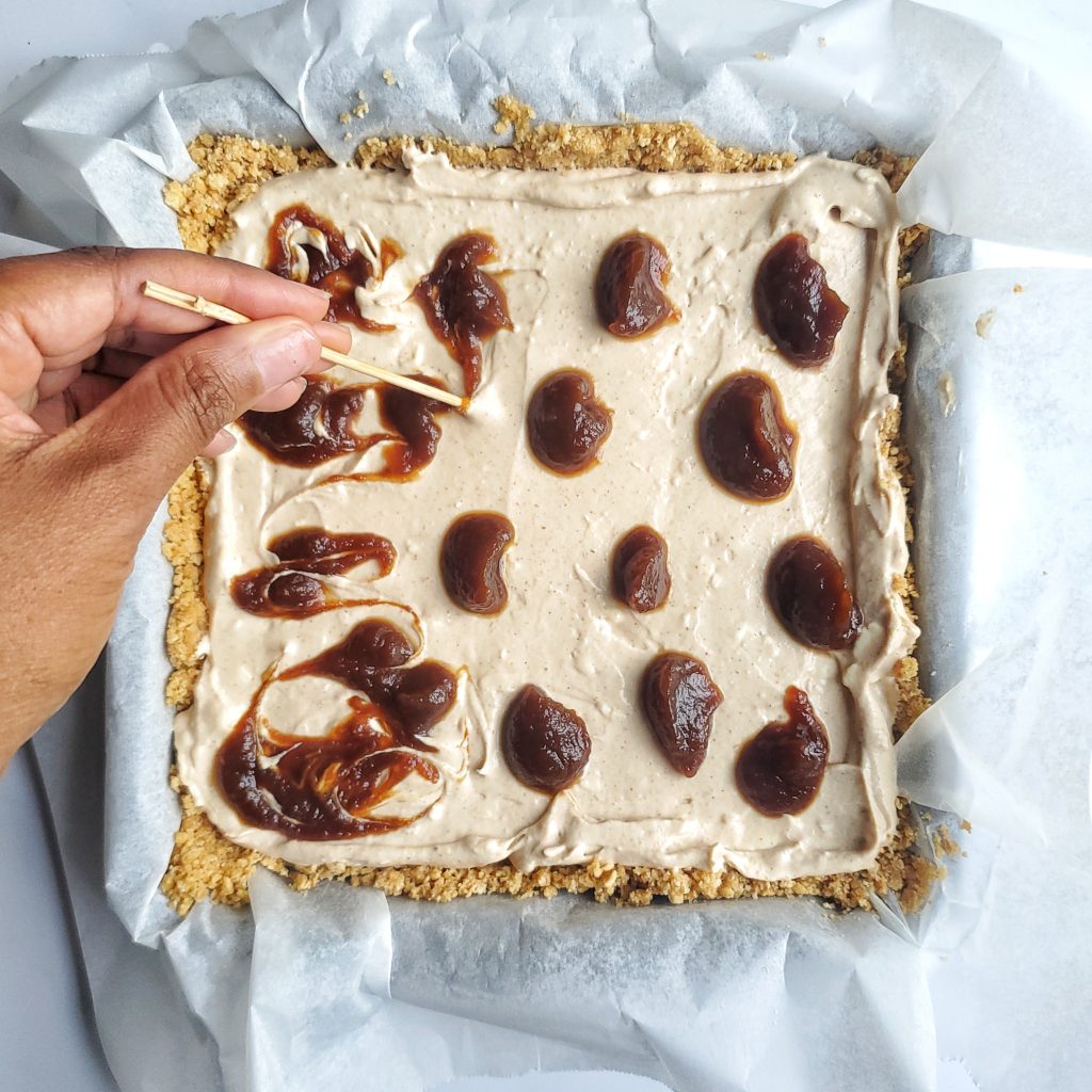 Overhead shot of no bake cheesecake with dollops of apple butter being swirled