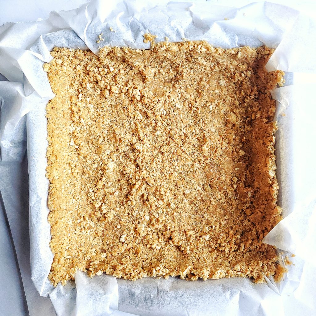 Overhead shot of graham cracker crust in a square pan