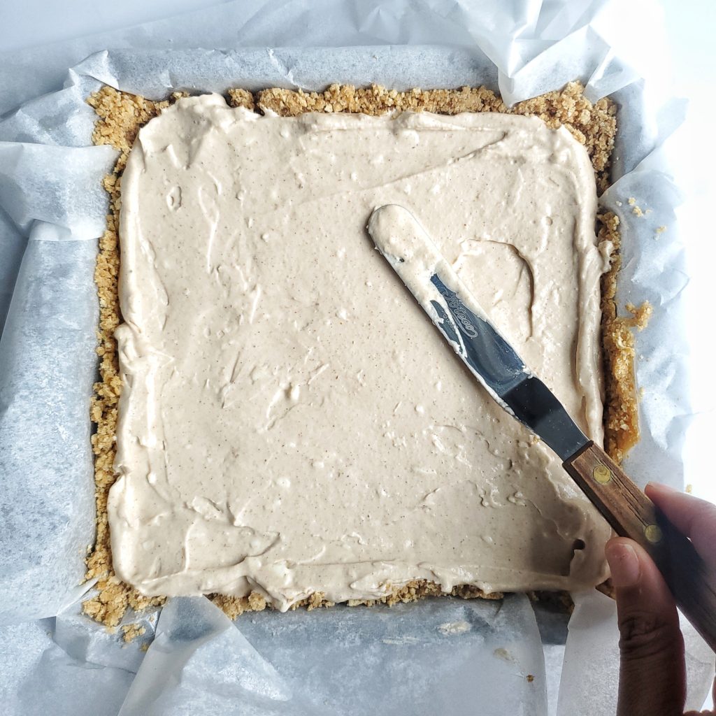 Overhead shot of no bake cheesecake filling being spread into a graham cracker crust