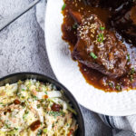 Overhead close up of braised short ribs with a bowl of creamy slaw