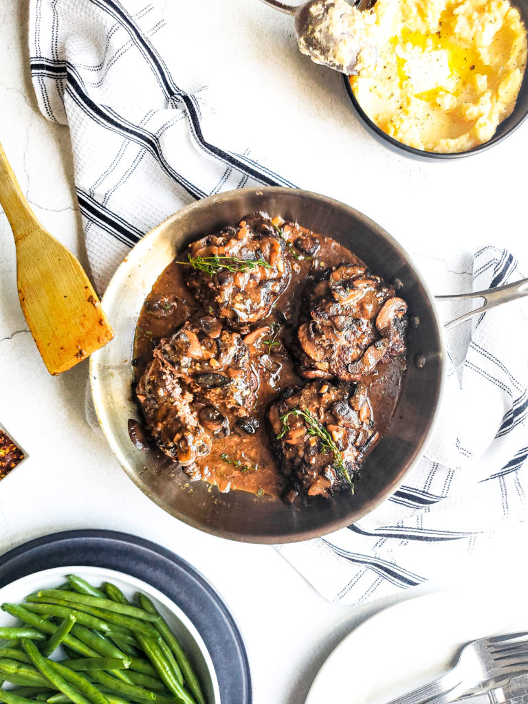 Smothered hamburger steaks with mushrooms in a pan
