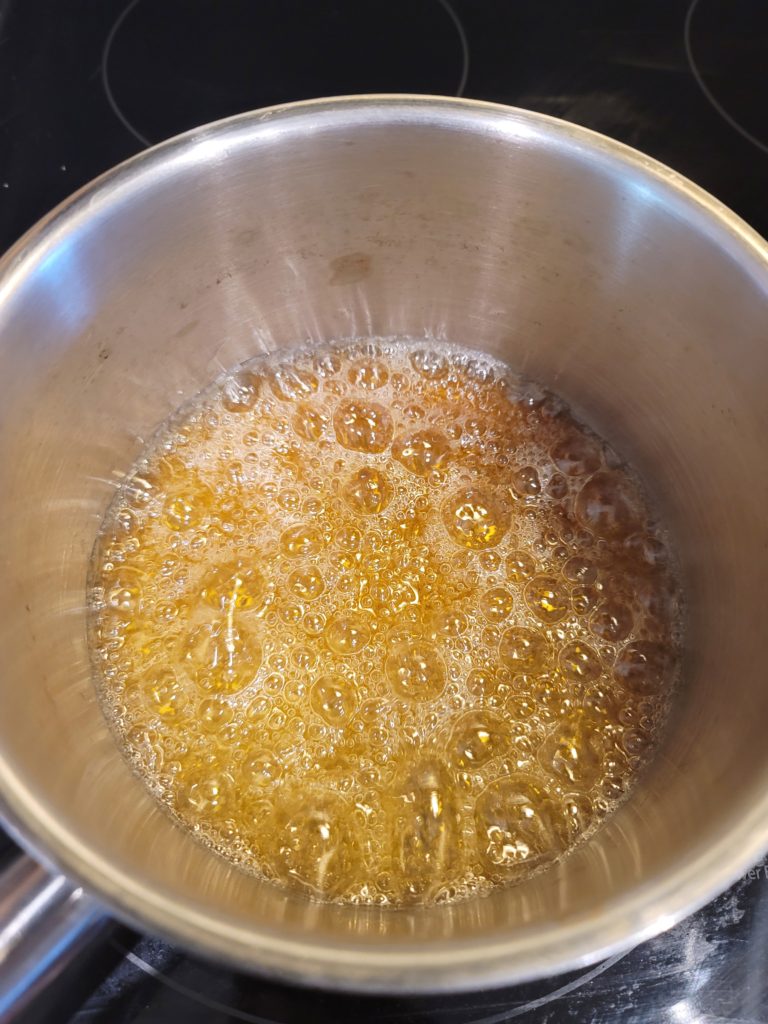 Sugar and water caramelizing in a small sauce pot