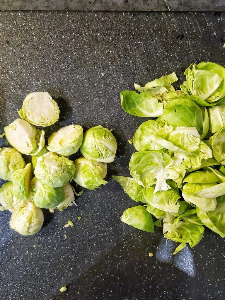 Brussels sprouts halves and leaves on a cutting board