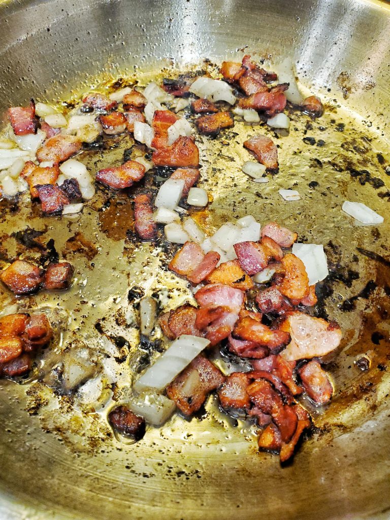 Diced bacon and onions cooking in a saute pan
