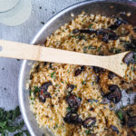 Close up of a pan full of mushroom risotto with a wooden spoon